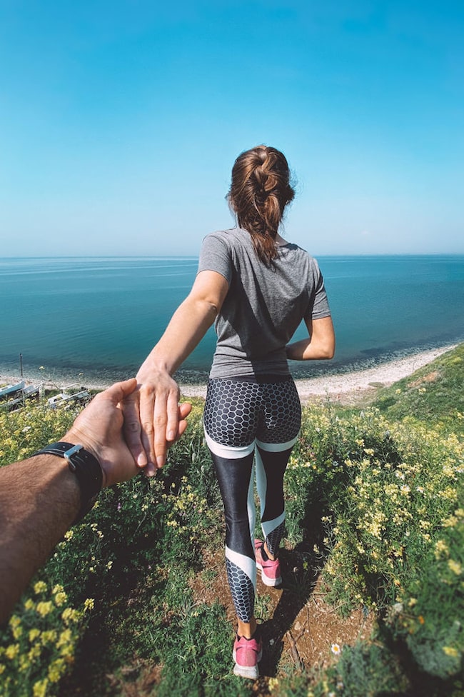 Frau in Sportkleidung blickt auf Meer, Ausblick, Partnerschaft