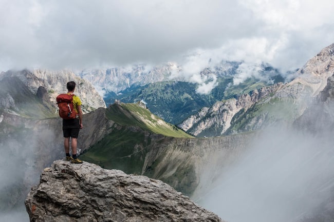 Wanderer steht auf einer Bergspitze und schaut in die Ferne