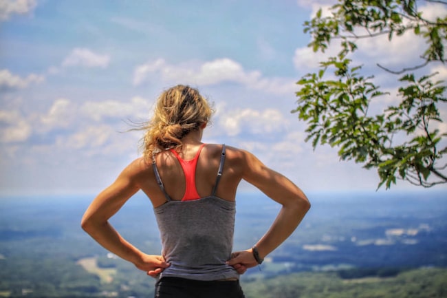 Sportlerin von hinten schaut in ein Tal