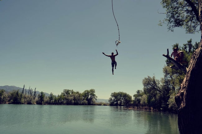 Mann macht einen Seilsprung in einen Badesee, Wasser, See, Naturbadesee, schwimmen, Seil, Sprung ins Wasser