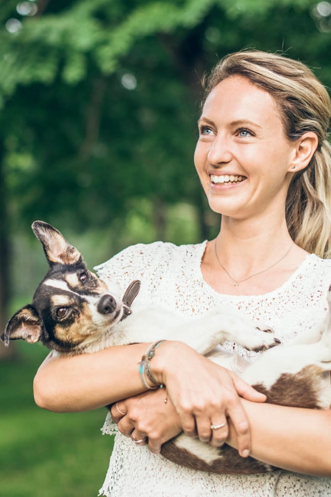 Entspannt lächelnde Frau mit einem kleinen Hund im Arm