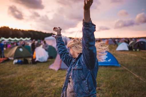 Frau schwingt ihre Arme durch die Luft und tanzt ausgelassen auf einem Campingplatz