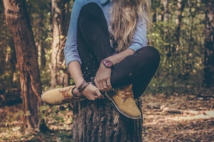 Frau sitzt auf Baumstamm im Herbstwald