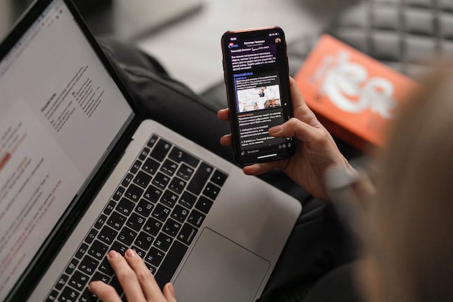 Frau liest am Laptop und Handy gleichzeitig die Medien