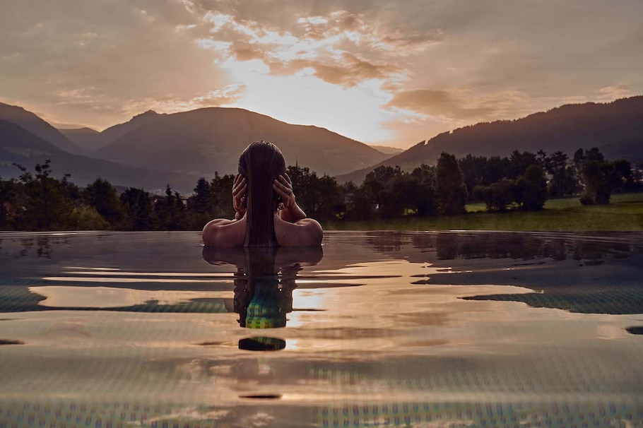 Eine Frau sieht sich den Sonnenuntergang im Wellness-Pool an.