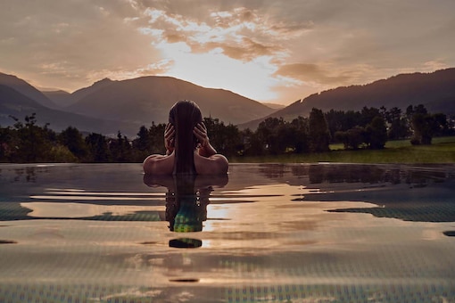 Eine Frau sieht sich den Sonnenuntergang im Wellness-Pool an.