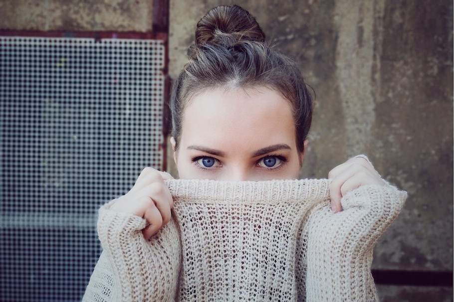 Frau, versteckt Gesicht hinter Pulli