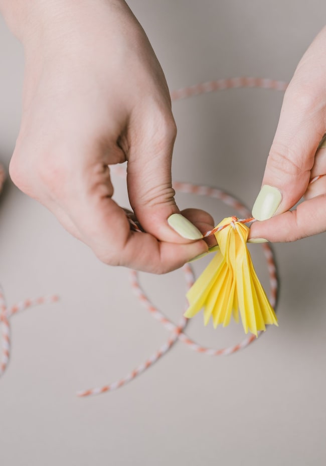 Hand bindet Schnur um Papierblüte