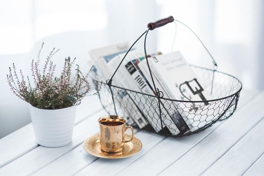 5 Bücher in einem Metallkorb auf einem Tisch mit einer Lavendelplfanze und Kaffee