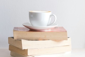 4 Bücher auf Stapel mit frischem Capuccino.