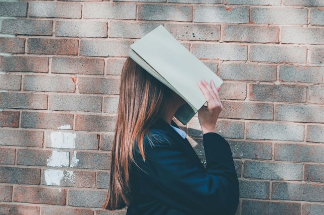 Frau bedeckt Gesicht mit Buch