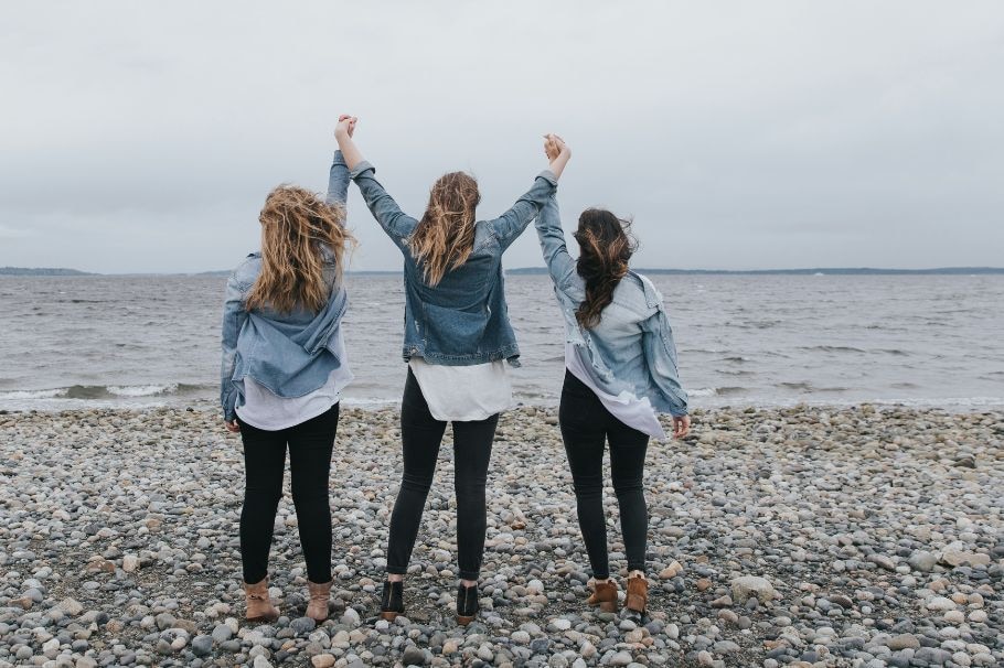 Drei Frauen, von hinten, mit erhobenen Armen, am See. Power-Pose.