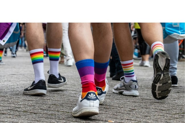 Füße von hinten, mit regenbogenfarbigen Socken. Symbol für LGBQT-Community.