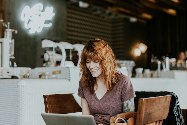 Frau vor Computer lächelnd, im Café