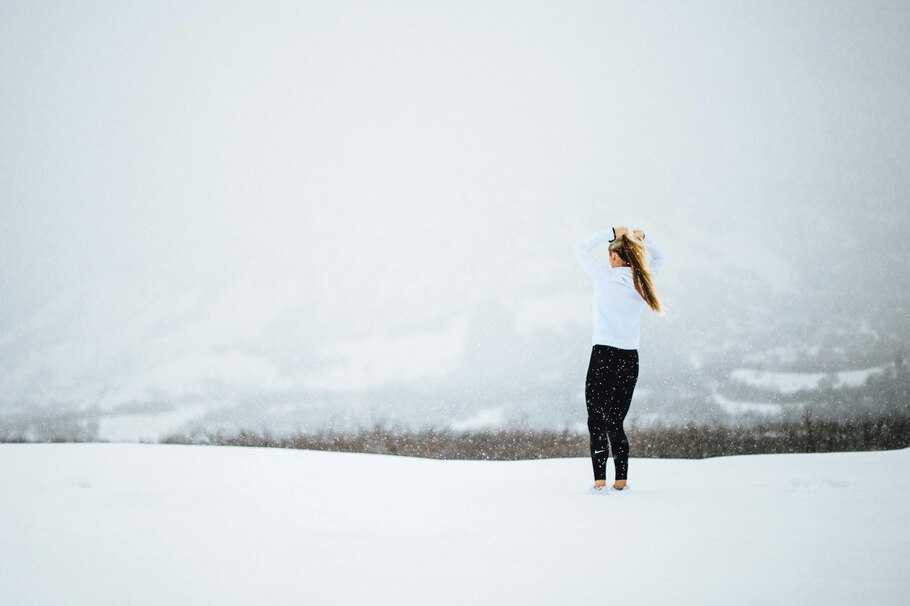 Frau in Joggingbekleidung in hügeliger Winterlandschaft