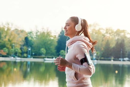 Frau läuft mit Kopfhörern, Joggerin, Laufen, Laufsport am See