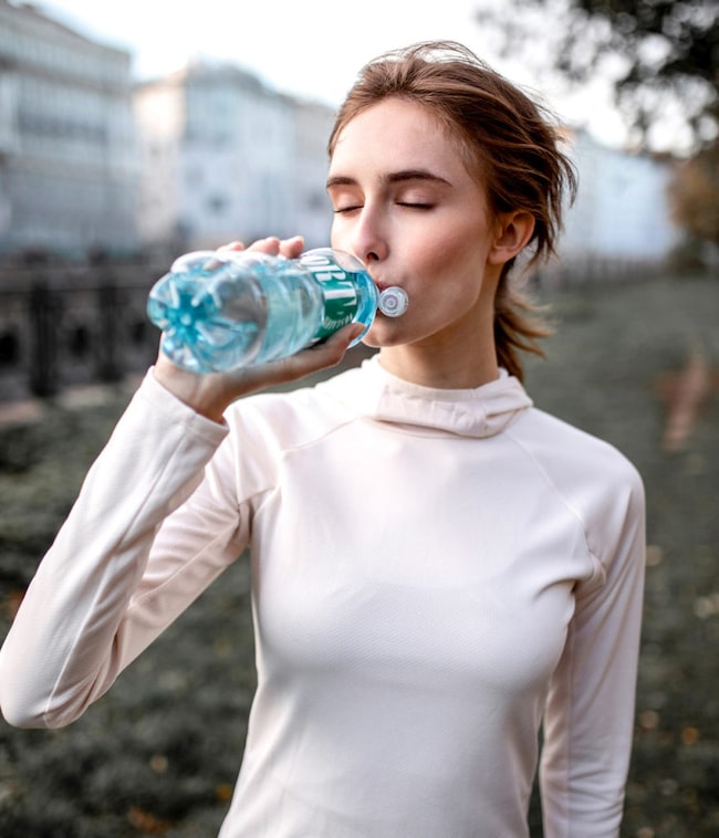 Eine Frau trinkt aus einer Vöslauer Flasche, Wasser trinken, stay hydrated, Frau, Wasserflasche