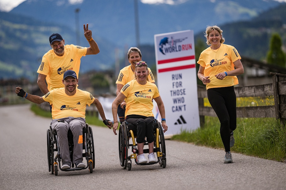 Läufer und Rollstuhlfahrer jubeln gemeinsam beim Wings for Life World Run.