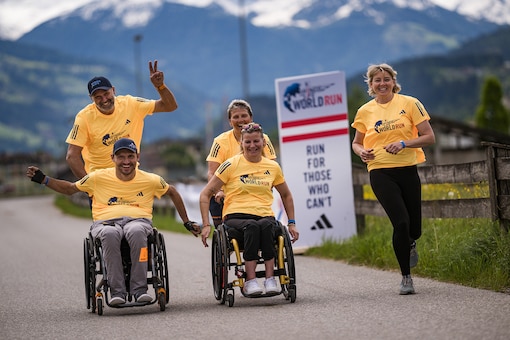 Läufer und Rollstuhlfahrer jubeln gemeinsam beim Wings for Life World Run.